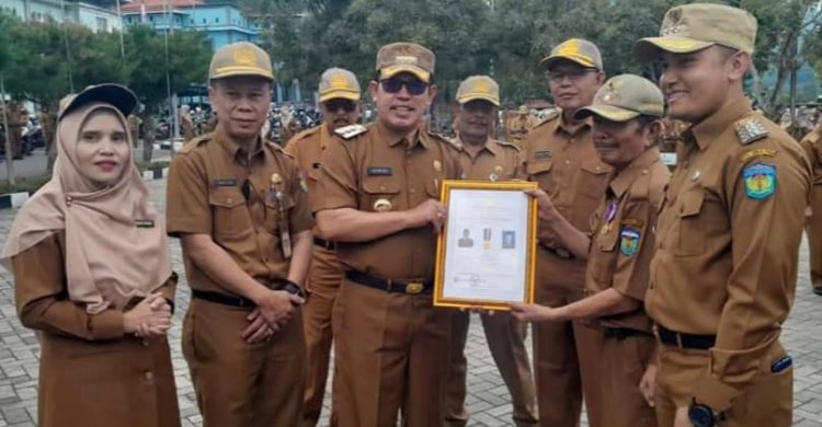 Walikota Sungai Penuh, Ahmadi Zubir, menyerahkan penghargaan secara simbolis kepada perwakilan Kepala Desa dari 58 Desa dalam Kota Sungai Penuh saat upacara dan apel kerja, Senin (26/12) pagi/ Foto: Alan /Ampar